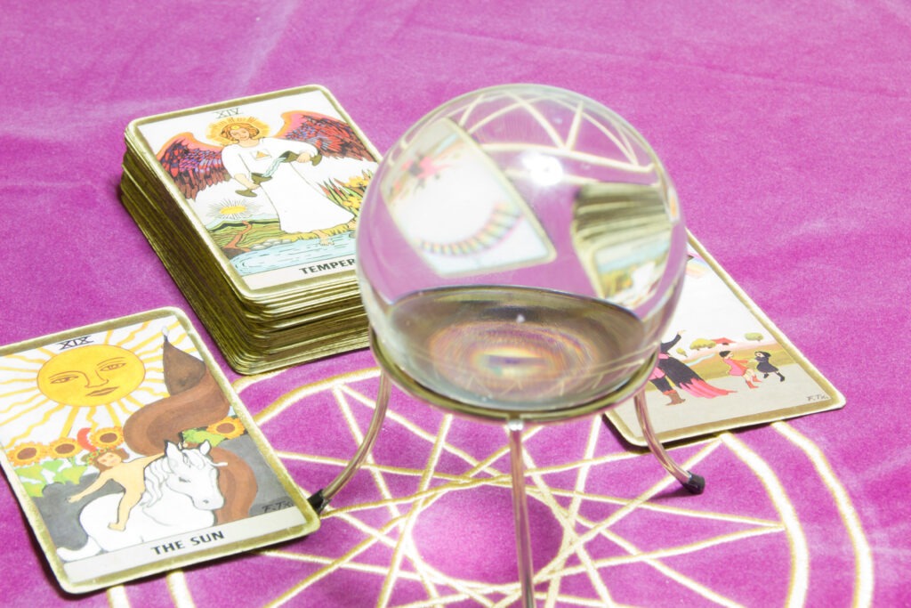 Crystal ball rests on a stand beside tarot cards