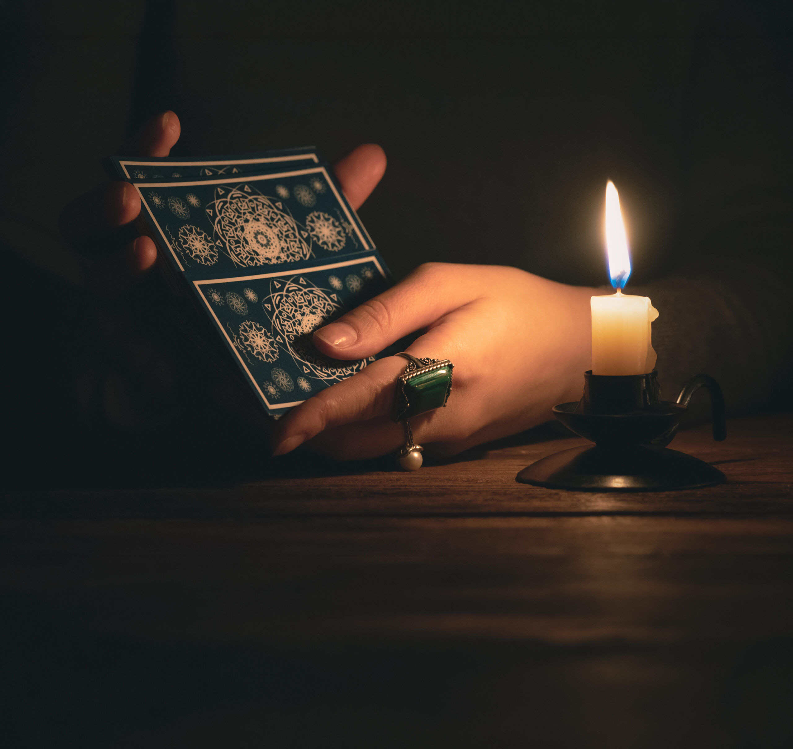 A hand holds intricate blue tarot cards