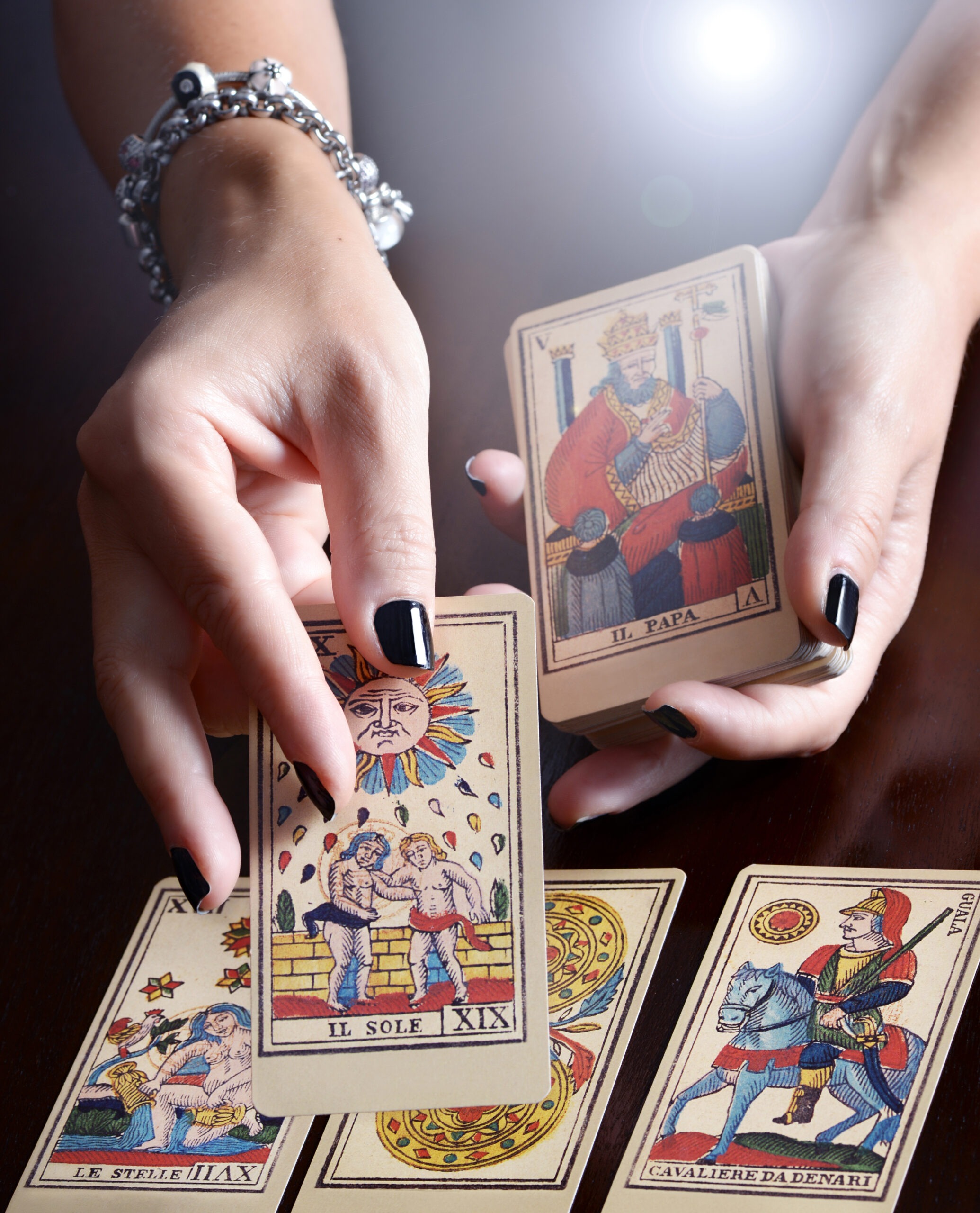 Hands holding tarot cards, prominently featuring 'Il Sole' and 'Il Papa.'