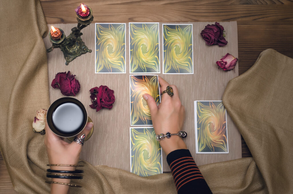 A hand reaches toward tarot cards arranged on a table